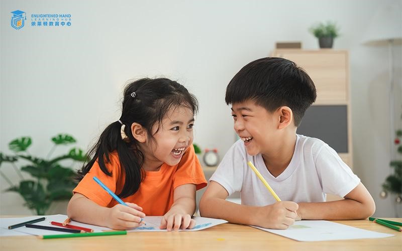 Two kids drawing at a desk with joy